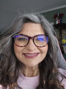 Portrait of Melinda, creator of The Bloom, smiling warmly in a calm, natural setting.